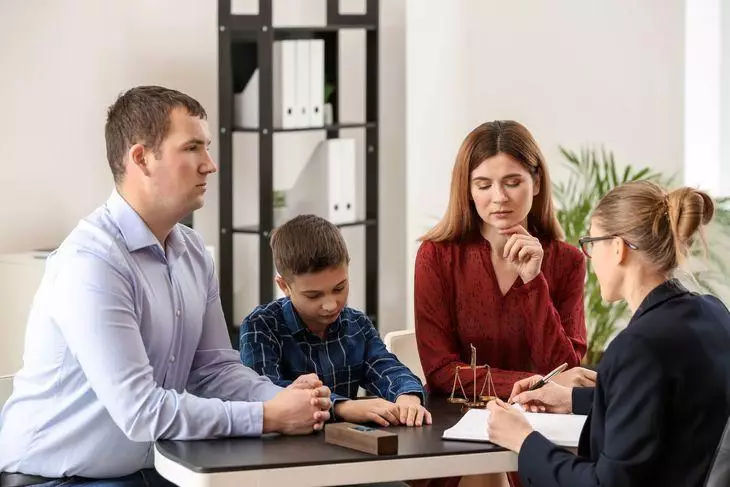 A lawyer, in the presence of parents and a child, fills out a document